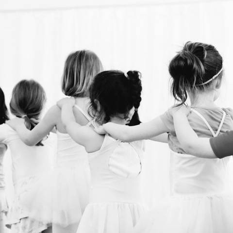 Kinder stehen Arm in Arm in einer Reihe im Tanzsaal